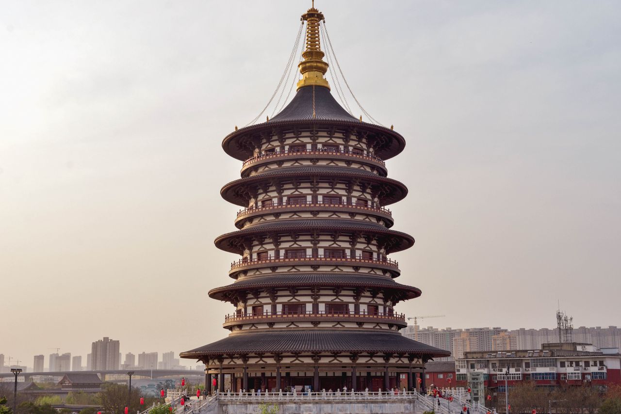 A stunning view of a traditional Chinese pagoda against a city skyline during sunset.
